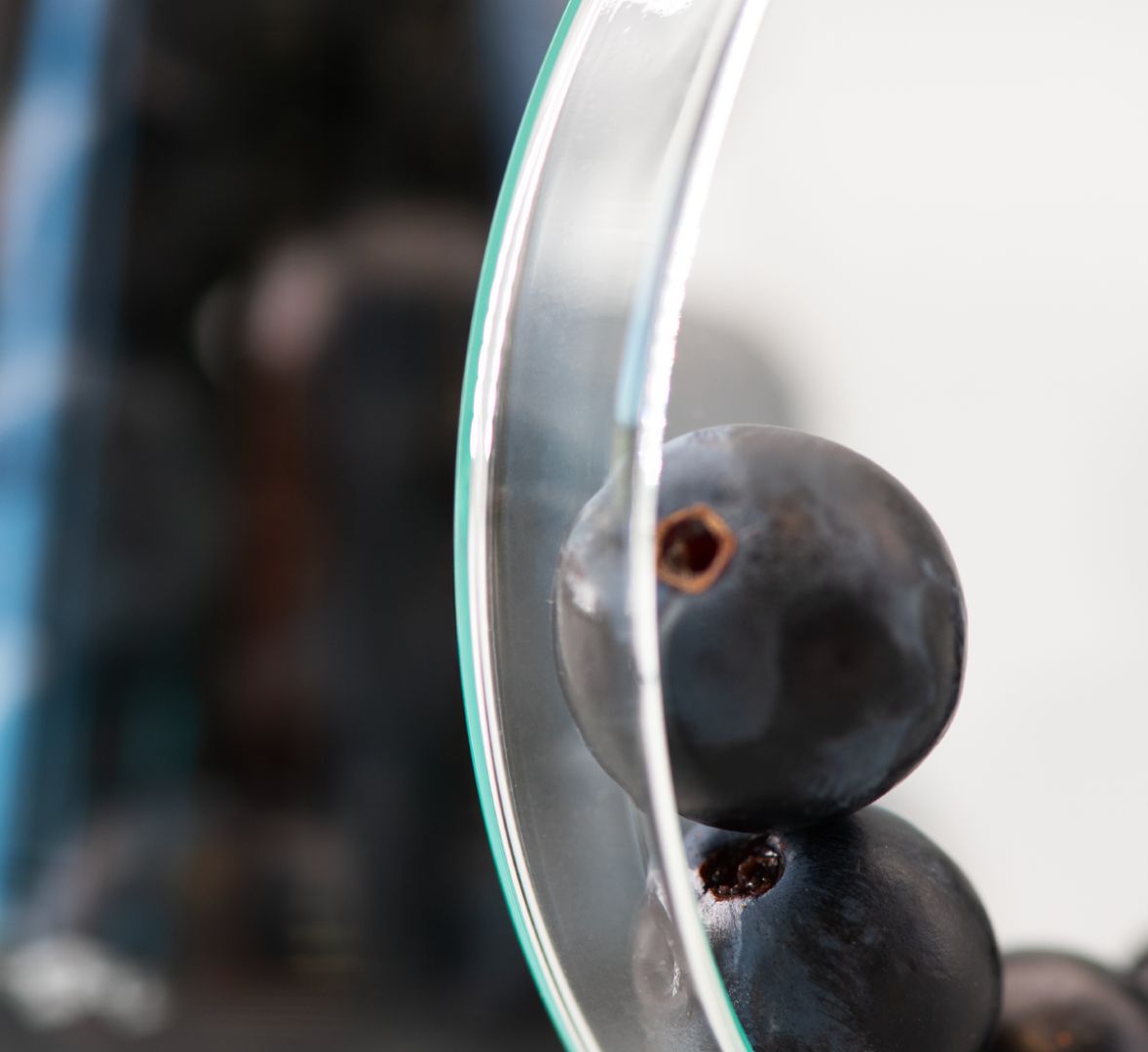 Raisins empilés contre une surface en verre, photographiés en macro avec un fond flou
