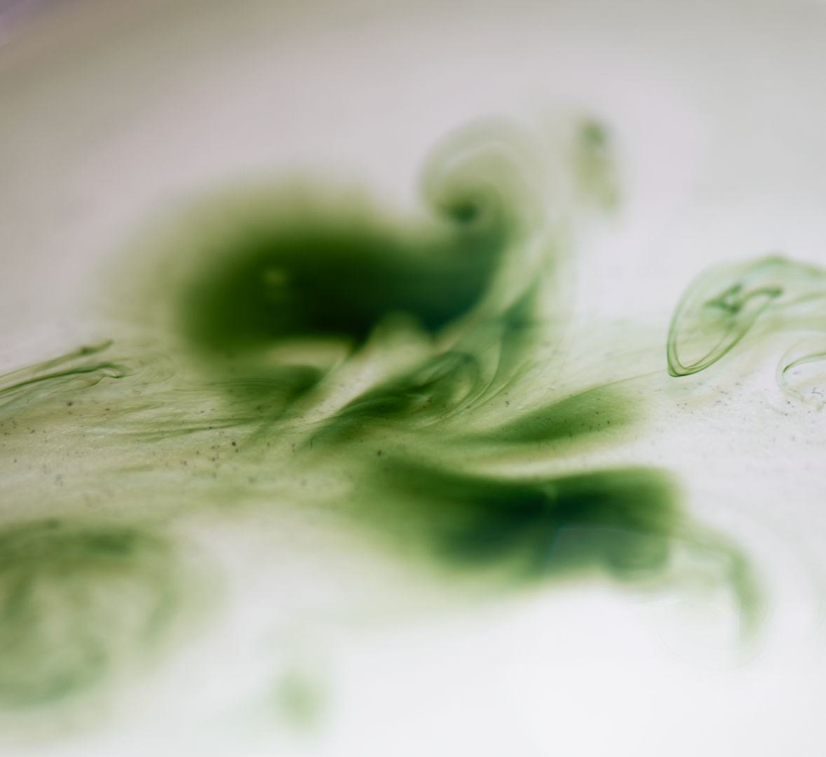 Pigments verts inspirés d’extraits végétaux se diffusant dans un liquide, symbolisant la concentration d’actifs naturels