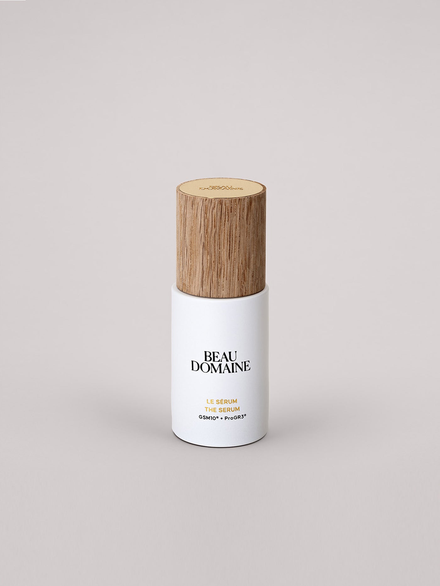 Le Sérum avec un capuchon en bois texturé sur un fond clair